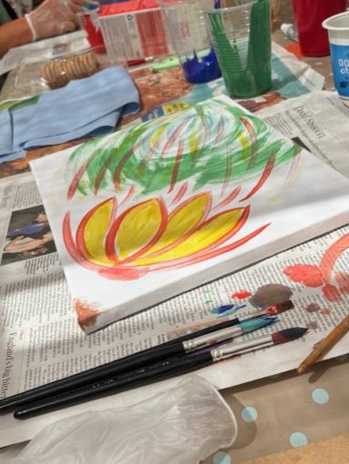 A bright abstract painting on a table with brushes and paint supplies nearby.