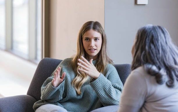 Two women engaged in conversation, one gesturing expressively.