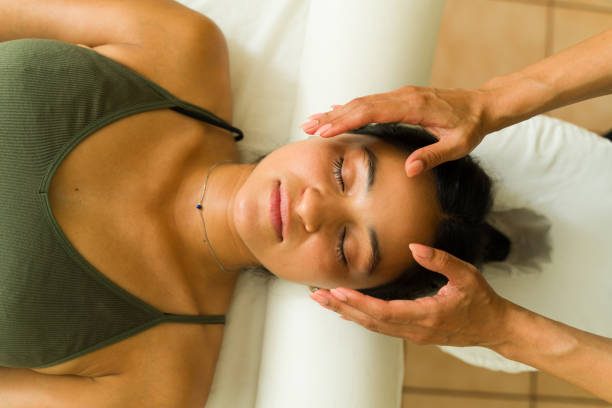 A woman receiving a facial massage while lying on a massage table.