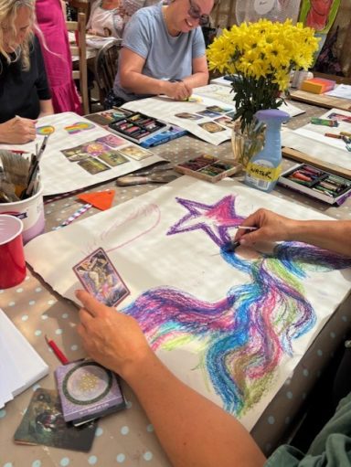 A group engaging in artistic activities with vibrant colours and flower arrangements on a table.