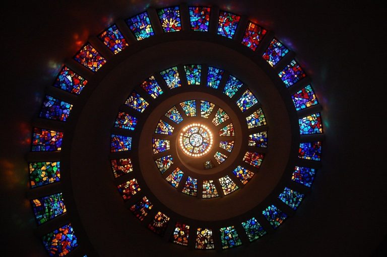 A colourful spiral of stained glass windows illuminated from the centre.