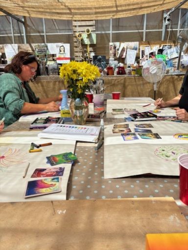 People engaged in arts and crafts at a table adorned with flowers and various supplies.