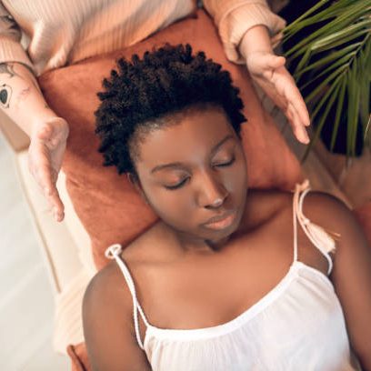 A person receiving a relaxation treatment with hands positioned over them.