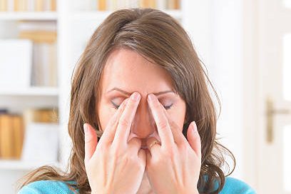 EFT Woman performing a relaxation technique, fingers on her forehead in a calm setting.