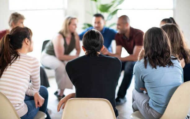 A group of people sitting in a circle, engaged in a discussion.